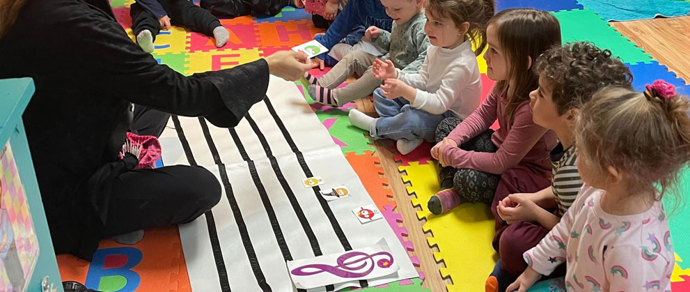 Enfants de garderie assis, plaçant des notes de musique sur une portée